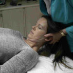 A woman is getting her head shaved by an esthetician.